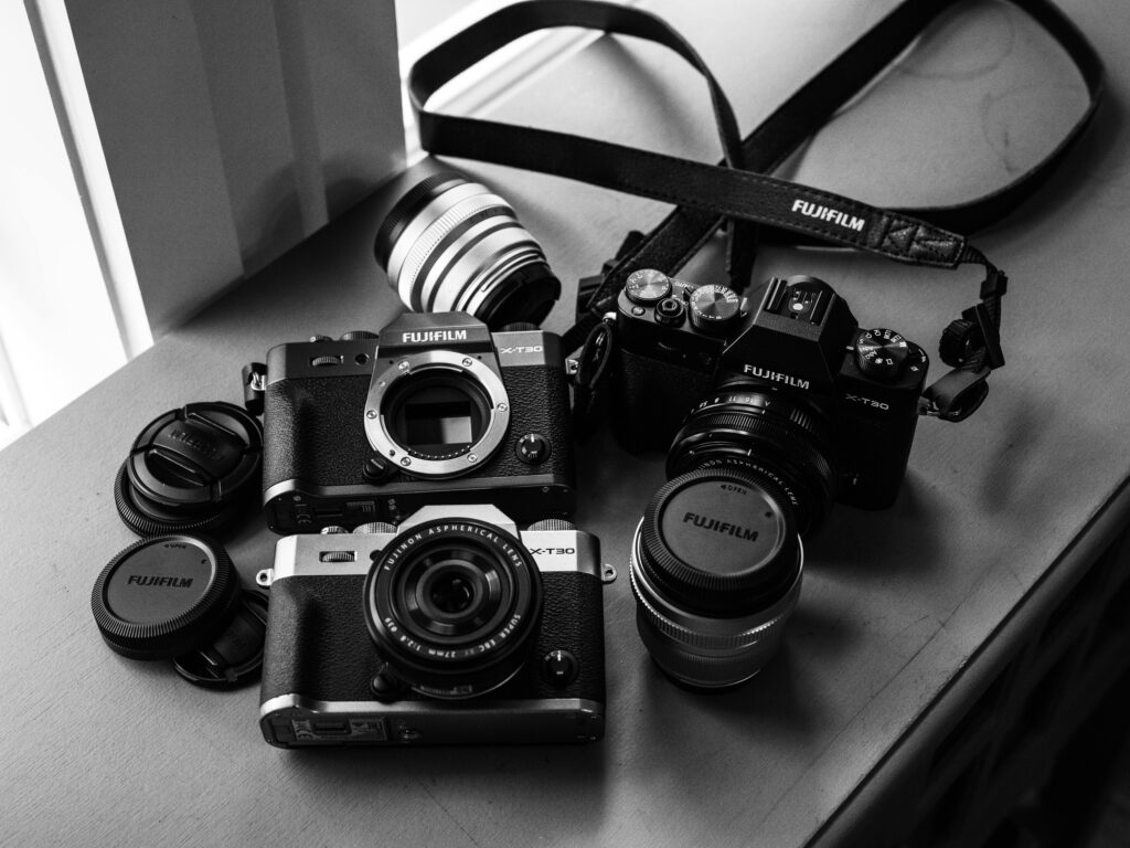 pexels-photo-3497126-3497126 A collection of vintage Fujifilm analog cameras and lenses displayed on a table in monochrome.