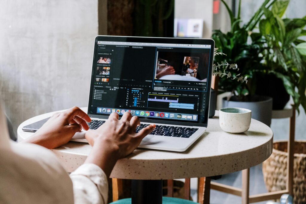 pexels-photo-5054208-5054208 Freelance video editor working on a laptop in a cafe setting, utilizing Adobe software.